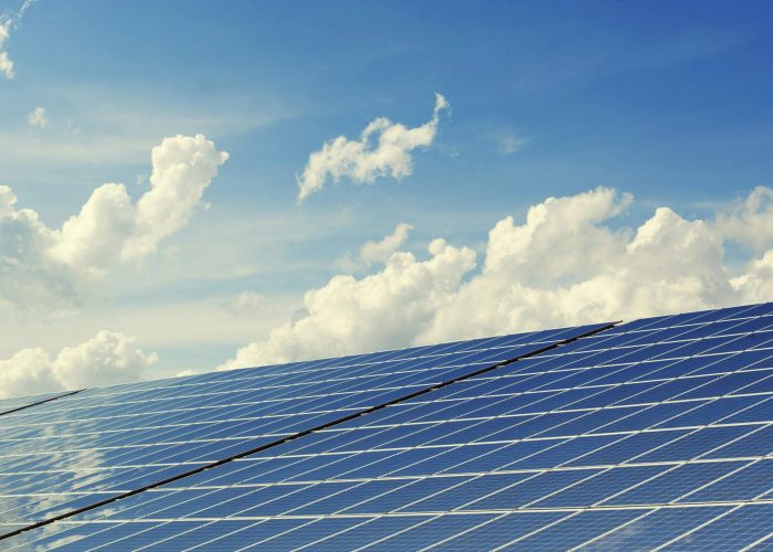 Sleek modern solar panels under a vibrant blue sky with clouds, symbolizing clean energy.