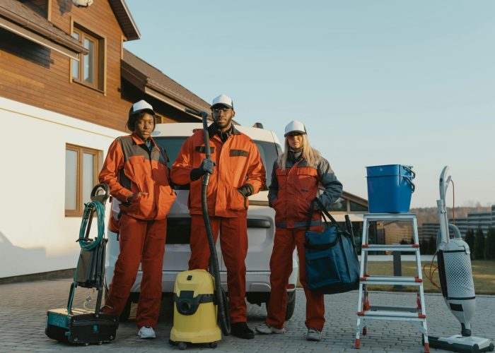 Group of workers in protective gear standing beside equipment outdoors.